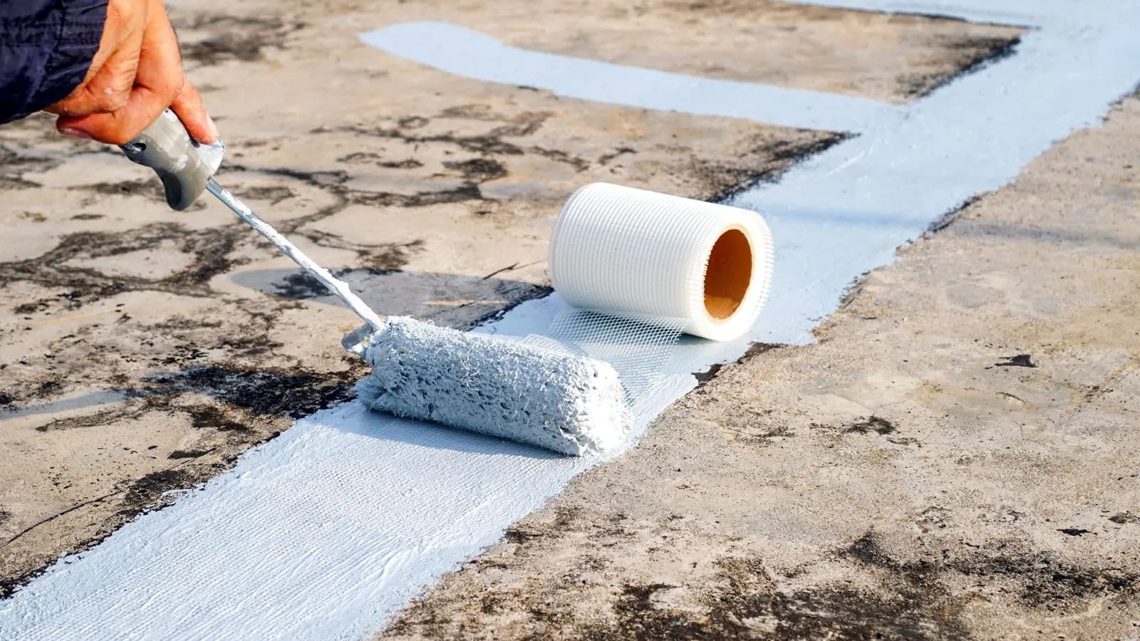 Protective coating being rolled onto a flat roof